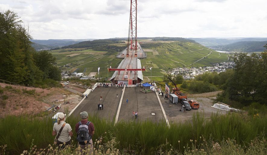 A man and a woman look down to the construction site of the Hochmoselbruecke, a bridge over the river Mosel near the village Zeltingen-Rachtig, Germany, Friday, Aug. 24, 2018. (Thomas Frey/dpa via AP)