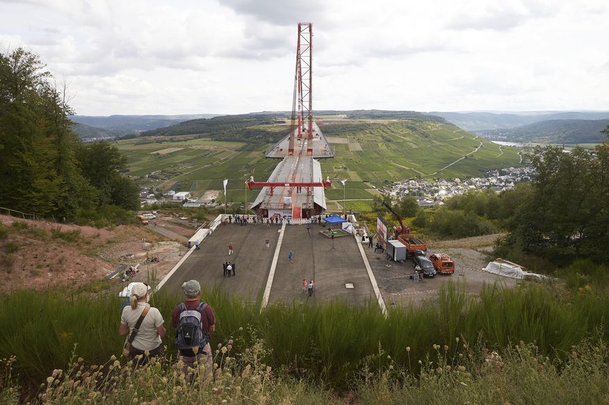 A man and a woman look down to the construction site of the Hochmoselbruecke, a bridge over the river Mosel near the village Zeltingen-Rachtig, Germany, Friday, Aug. 24, 2018. (Thomas Frey/dpa via AP)