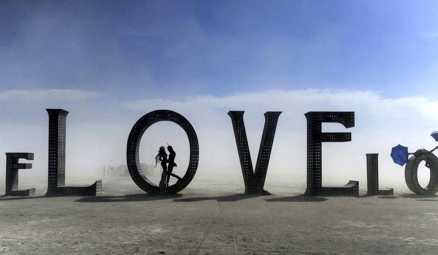 In this Aug. 30, 2014 photo, a couple stands inside a love sculpture at Burning Man on the Black Rock Desert of Gerlach, Nev. The #MeToo movement is making its way to Burning Man which begins Aug. 26-Sept. 3, 2018. Organizers are reminding attendees that just because the counterculture festival in the Nevada desert is known for occasional nudity and kinky landmarks like the "Orgy Dome," it doesn't mean it’s a free-for-all when it comes to touching or non-consensual sex. (Andy Barron/The Reno Gazette-Journal via AP)