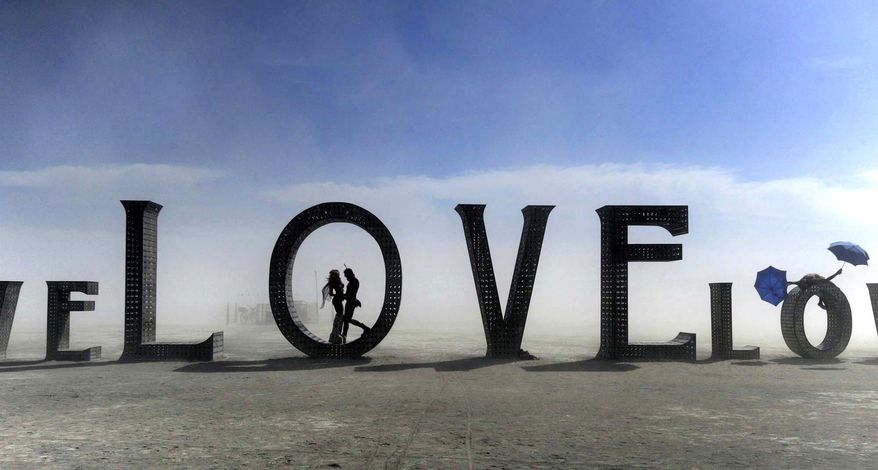 In this Aug. 30, 2014 photo, a couple stands inside a love sculpture at Burning Man on the Black Rock Desert of Gerlach, Nev. The #MeToo movement is making its way to Burning Man which begins Aug. 26-Sept. 3, 2018. Organizers are reminding attendees that just because the counterculture festival in the Nevada desert is known for occasional nudity and kinky landmarks like the "Orgy Dome," it doesn't mean it’s a free-for-all when it comes to touching or non-consensual sex. (Andy Barron/The Reno Gazette-Journal via AP)