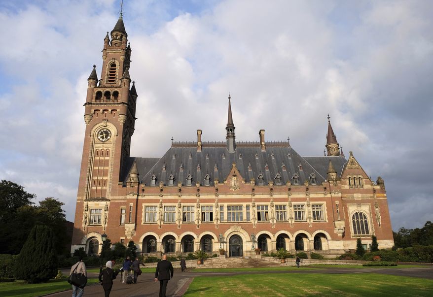 People walk toward the International Court of Justice in the Hague, the Netherlands, Monday Aug. 27, 2018. Iran is going to the United Nations' highest court in a bid to have U.S. sanctions lifted. Iran filed the case with the International Court of Justice in July, claiming that sanctions the Trump administration imposed on May 8 breach a 1955 bilateral agreement known as the Treaty of Amity that regulates economic and consular ties between the two countries. (AP Photo/Mike Corder)