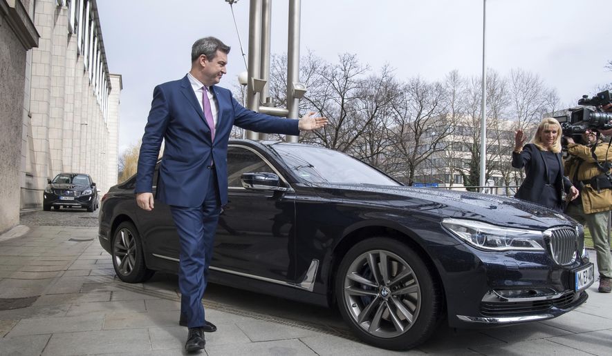 FILE - In this March 16, 2018 file photo new Bavarian governor Markus Soeder, left, and his wife Karin Baumueller-Soeder arrive at the Bavarian state chancellery in Munich, southern Germany. A German newspaper reports judges are considering jailing senior Bavarian officials for failing to take action against air pollution in Munich, home to automaker BMW. (Peter Kneffel/dpa via AP)