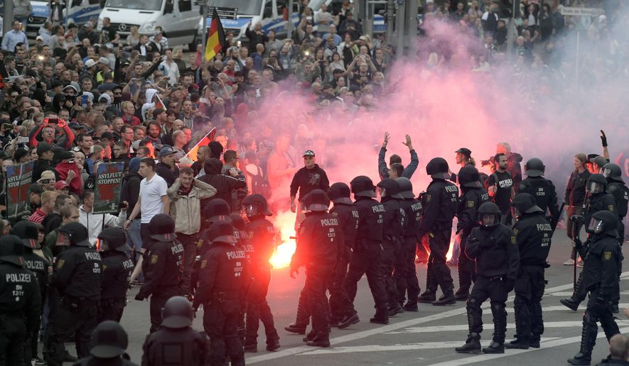 Protesters light fireworks during a far-right demonstration in Chemnitz, Germany, Monday, Aug. 27, 2018 after a man has died and two others were injured in an altercation between several people of "various nationalities" in the eastern German city of Chemnitz on Sunday. (AP Photo/Jens Meyer)