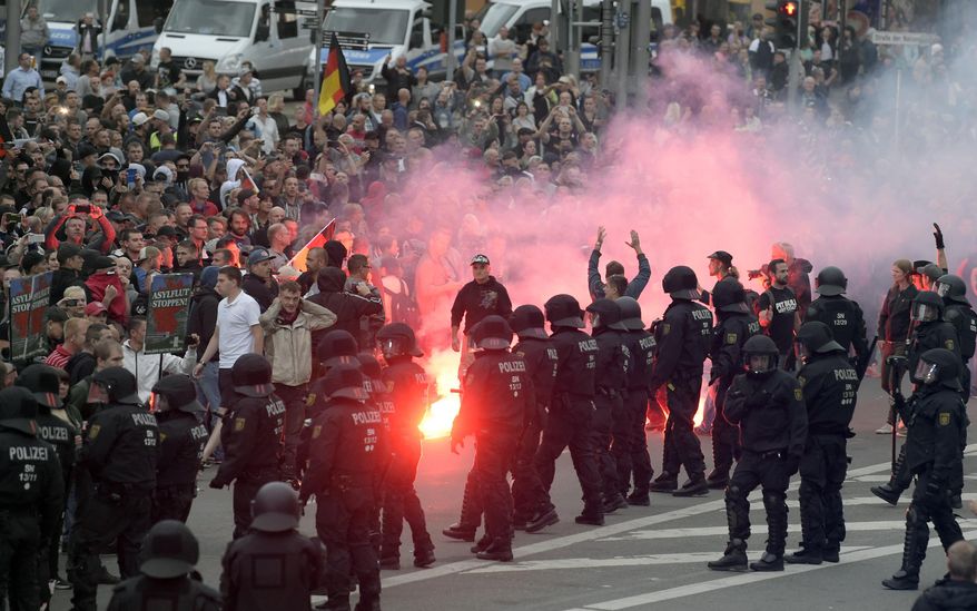 Protesters light fireworks during a far-right demonstration in Chemnitz, Germany, Monday, Aug. 27, 2018 after a man has died and two others were injured in an altercation between several people of "various nationalities" in the eastern German city of Chemnitz on Sunday. (AP Photo/Jens Meyer)