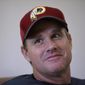 In this June 13, 2018, photo, Washington Redskins coach Jay Gruden is interviewed by The Associated Press after NFL football practice in Ashburn, Va. With Jon Gruden leaving “Monday Night Football” to return to the sideline after a decade away, and Jay entering his fifth season as Redskins coach, they will join the Harbaughs as the only sets of siblings to simultaneously hold jobs as NFL head coaches. (AP Photo/Nick Wass, File)