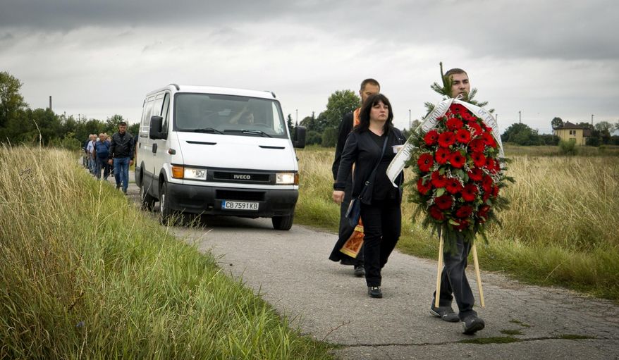 Bulgarians take part in a funeral for a victim of a bus crash, in Svetovrachene, Bulgaria, Tuesday, Aug. 28, 2018. A Bulgarian village just outside the capital has held funeral services for 15 of its residents who died in a bus crash over the weekend. Many of the 2,000 residents of Svetovrechane who came to pay final respects on Tuesday were related to the victims of the accident, which killed 17 people when a bus full of religious pilgrims overturned and fell off a highway about 50 kilometers (30 miles) north of Sofia. (AP Photo/Filip Dvorski)