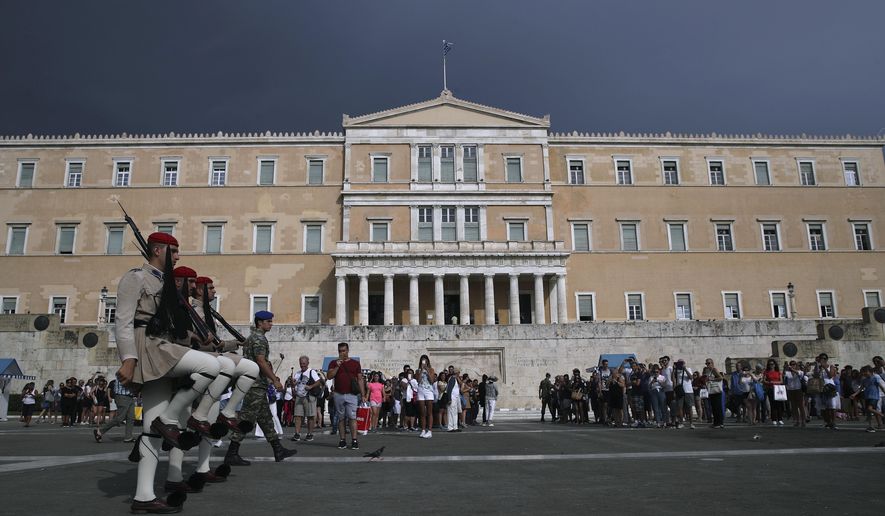 Greek Presidential guards take part in the changing of the guard ceremony as tourists watch, in front of the Parliament, central Athens, Tuesday, Aug. 28, 2018. (AP Photo/Petros Giannakouris)