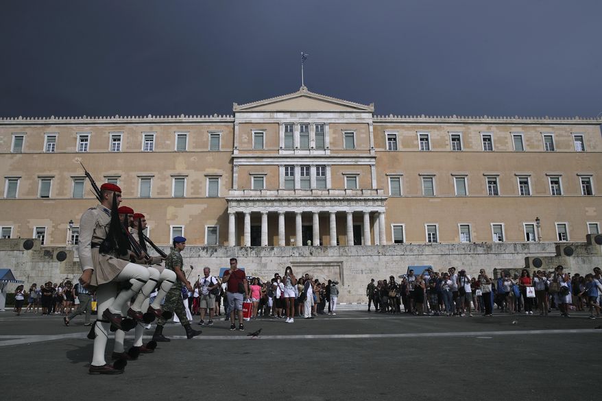 Greek Presidential guards take part in the changing of the guard ceremony as tourists watch, in front of the Parliament, central Athens, Tuesday, Aug. 28, 2018. (AP Photo/Petros Giannakouris)
