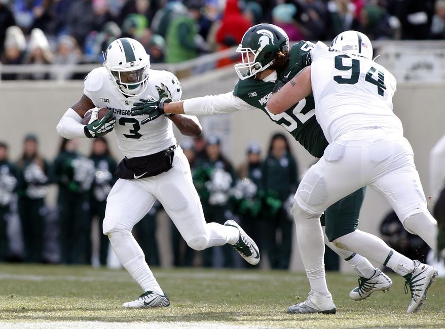 FILE - In this Saturday, April 7, 2018 file photo, Michigan State running back LJ Scott, left, rushes against defensive end Dillon Alexander as offensive lineman Chase Gianacakos (94) blocks during the first half of a spring NCAA college football scrimmage in East Lansing, Mich. The NFL can wait for now. LJ Scott is back at Michigan State with a list of areas he’d like to shore up. Scott’s return after his junior season was big news for the Spartans, who now look like Big Ten title contenders in 2018. (AP Photo/Al Goldis)