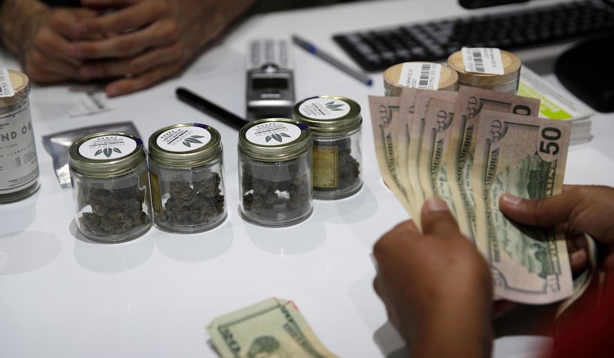 FILE - In this July 1, 2017 file photo, a person buys marijuana at the Essence cannabis dispensary in Las Vegas. The first full year of legalized marijuana for recreational use in Nevada pushed taxable pot sales past the $500 million mark statewide and raised nearly $70 million in tax revenue, including $27.5 million for schools. The Nevada Department of Taxation said Tuesday, Aug. 28, 2018 the $529.9 million in taxable pot sales for recreational and medical use combined exceeded expectations by 40 percent for the fiscal year that ended June 30. (AP Photo/John Locher, File)