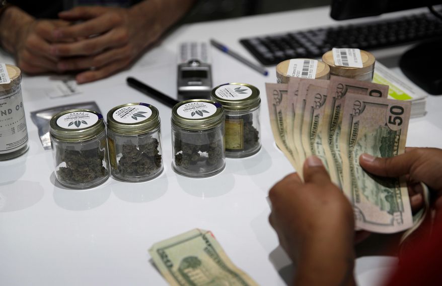 FILE - In this July 1, 2017 file photo, a person buys marijuana at the Essence cannabis dispensary in Las Vegas. The first full year of legalized marijuana for recreational use in Nevada pushed taxable pot sales past the $500 million mark statewide and raised nearly $70 million in tax revenue, including $27.5 million for schools. The Nevada Department of Taxation said Tuesday, Aug. 28, 2018 the $529.9 million in taxable pot sales for recreational and medical use combined exceeded expectations by 40 percent for the fiscal year that ended June 30. (AP Photo/John Locher, File)