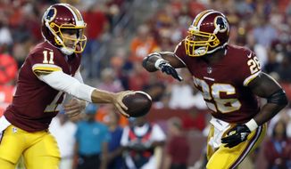 File-This Aug. 24, 2018, file photo shows Washington Redskins quarterback Alex Smith (11) handing the ball off to running back Adrian Peterson (26) during the first half of a preseason NFL football game against the Denver Broncos in Landover, Md. Smith and Peterson sat a few feet away from each other as fresh-faced college players at the Heisman Trophy ceremony in New York in late 2005 and never imaged this would happen. Twelve NFL seasons later for Smith and 11 for Peterson and they’re now in the same backfield together with the Washington Redskins.  (AP Photo/Alex Brandon) ** FILE **