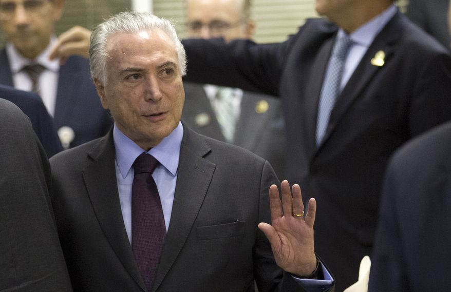 Brazils' President Michel Temer greets the media as he arrives for an update on the federal security intervention in Rio de Janeiro, Brazil, Thursday, Aug.30, 2018. (AP Photo/Silvia Izquierdo)