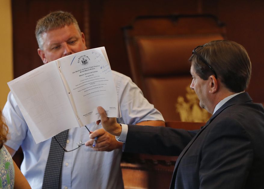 Senate President Michael D. Thibodeau, left, reads the Senate's Advance Journal and Calendar being held by Sen. Troy Jackson, D-Aroostock, prior to the start of a special session, Thursday, Aug. 30, 2018, in Augusta, Maine. Lawmakers returned to deal with Maine's struggling child welfare system and the state's tax code. (AP Photo/Robert F. Bukaty)