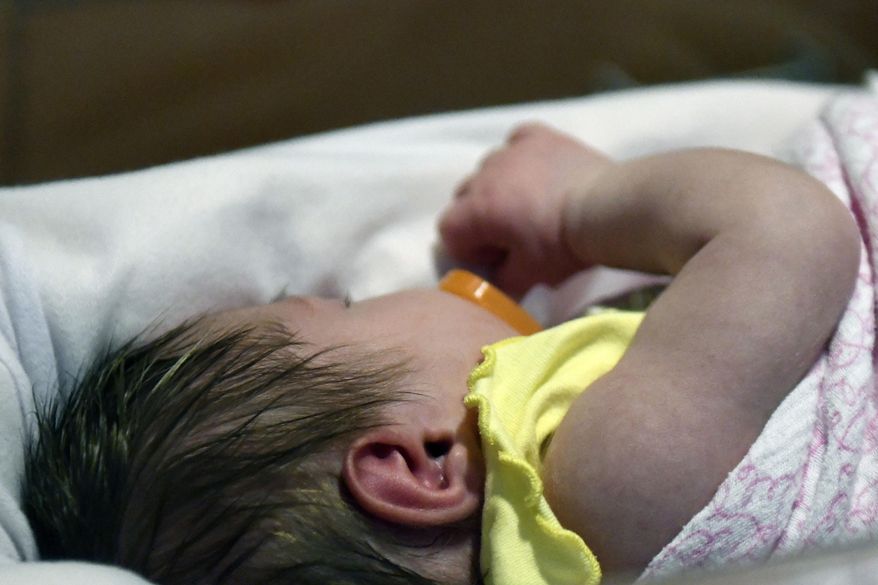 In this Feb. 13, 2018, photo, a week-old baby lies in a neonatal intensive care unit bay at the Norton Children's Hospital in Louisville, Ky. This particular NICU is dedicated to newborns of opioid-addicted mothers, who are suffering with newborn abstinence syndrome. The area is kept dark and quiet due to increased production of neurotransmitters in newborns of addicted mothers, which can disrupt the nervous system and overstimulate bodily functions. (AP Photo/Timothy D. Easley) **FILE**