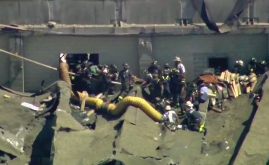 This aerial frame grab from video by WFLD-TV in Chicago shows rescue personnel at the scene where several people were reported trapped inside a Chicago water reclamation plant after a fire and possible explosion caused part of the building's roof to collapse Thursday, Aug. 30, 2018. (WFLD-TV via AP)