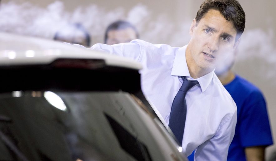 Prime Minister Justin Trudeau uses a smoke wand during a demonstration of air flow over a car during a visit to the University of Ontario&#39;s Institute of Technology in Oshawa, Ontario, Friday, Aug. 31, 2018. (Chris Young/The Canadian Press via AP)