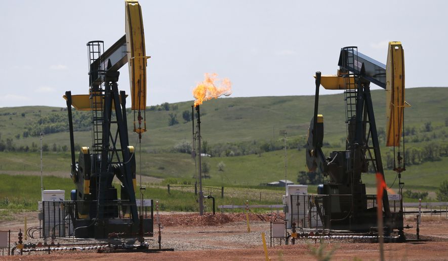 In this June 12, 2014 file photo, natural gas is burned off near pumps in Watford City, N.D. As Trump rolls back some Obama-era rules on climate-changing methane pollution, Colorado officials say their regulations have reduced oil field leaks. A report released Thursday, Aug. 23, 2018, shows required state inspections helped find and repair 73,000 methane leaks over three years. (AP Photo/Charles Rex Arbogast, File)