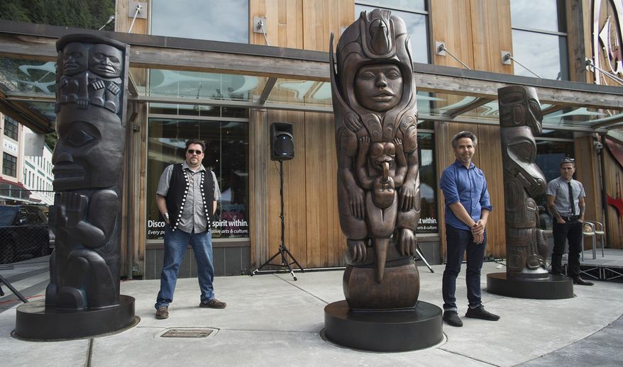 In this Aug. 26, 2018 photo, Tsimshian artist David R. Boxley, left, Tlingit artist Stephen Jackson, center, and Haida artist TJ Young, stand by their bronze house posts during an unveiling ceremony in front of the Walter Soboleff Center by Sealaska Heritage Institute in Juneau, Alaska. Each 8-foot-tall post at the corner of Front and Seward streets was carved respectively by a Tsimshian, Tlingit and Haida artist before casts were made and enduring, bronze versions were created in a Seattle foundry. (Michael Penn/The Juneau Empire via AP)