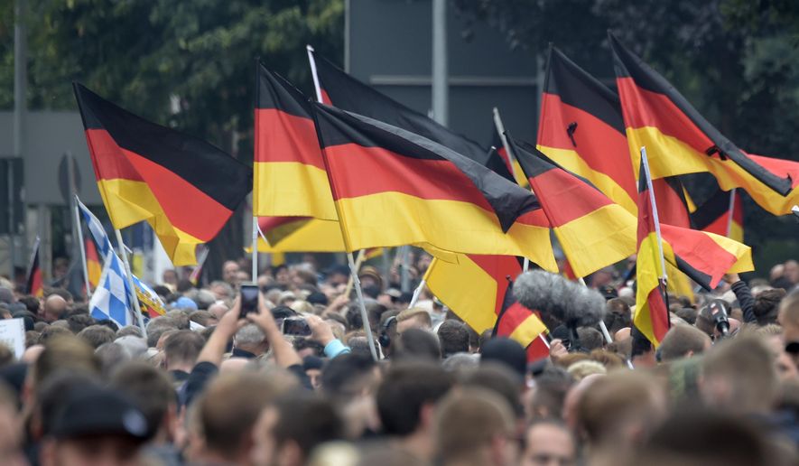 Demonstrators carry German flags during a demonstration in Chemnitz, eastern Germany, Saturday, Sept. 1, 2018, after several nationalist groups called for marches protesting the killing of a German man last week, allegedly by migrants from Syria and Iraq. (AP Photo/Jens Meyer)