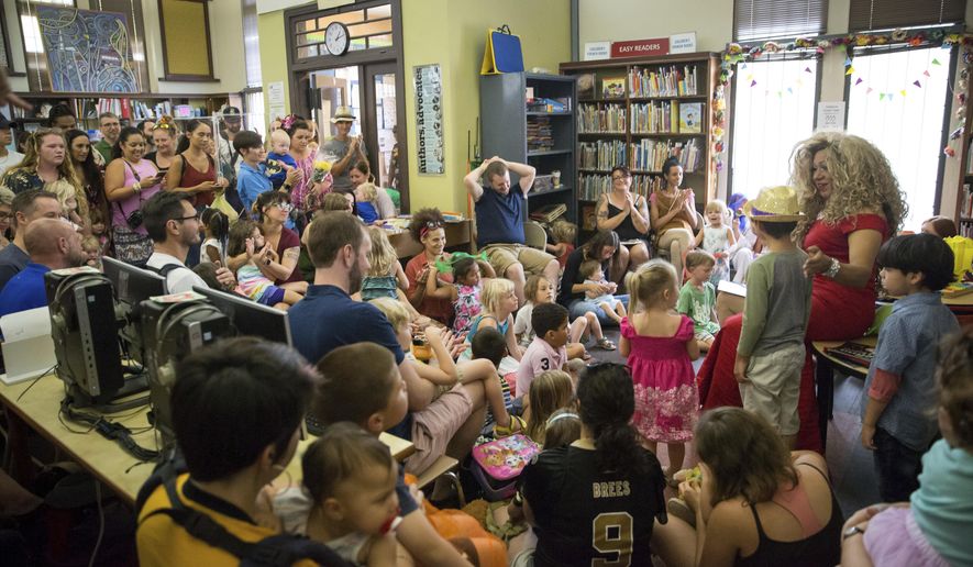 Vanessa Carr , right, reads to children during Drag Queen Story Time at the Alvar Library in New Orleans on Saturday, Aug. 25, 2018. Children and parents and caregivers packed into the library to hear drag queens Blazen Haven and Carr read stories and sing songs during the event. (Scott Threlkeld/The Advocate via AP) **FILE**