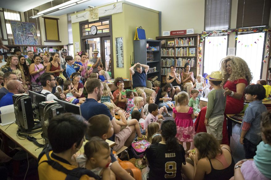 Vanessa Carr , right, reads to children during Drag Queen Story Time at the Alvar Library in New Orleans on Saturday, Aug. 25, 2018. Children and parents and caregivers packed into the library to hear drag queens Blazen Haven and Carr read stories and sing songs during the event. (Scott Threlkeld/The Advocate via AP) **FILE**
