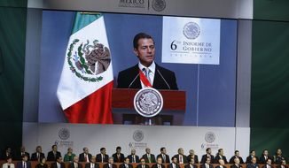 Mexican President Enrique Pena Nieto, seen on the screen, delivers his sixth and final State of the Nation address at the National Palace in Mexico City, Monday, Sept. 3, 2018. President-elect and longtime opposition leader Andres Manuel Lopez Obrador will take over the reigns of power on December 1. (AP Photo/Rebecca Blackwell)