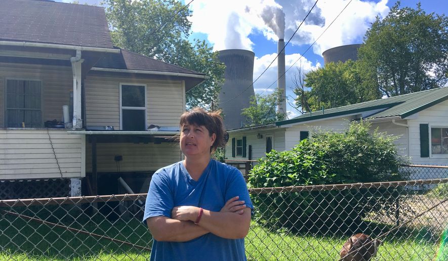 In this Aug. 23, 2018 photo, Andrea Maxey of Poca, W.Va., speaks outside her home with the American Electric Power’s John Amos coal-fired power plant is in the background across the Kanawha River in Winfield. Maxey says emissions from the plant aren’t a nuisance. President Donald Trump picked West Virginia where he announced rolling back pollution rules for coal-fired power plants. But he didn’t mention that the northern two-thirds of West Virginia, with the neighboring part of Pennsylvania, would be hit hardest. (AP Photo/John Raby)