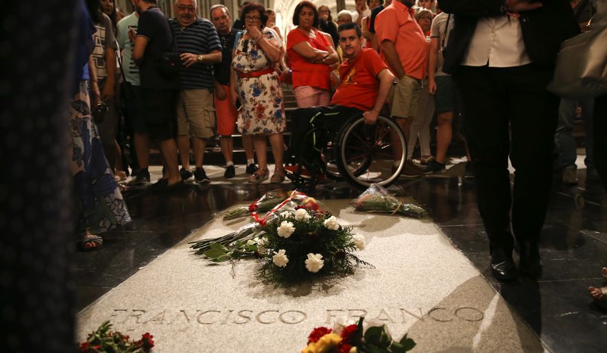 People stand around the tomb of former Spanish dictator Francisco Franco inside the basilica at the the Valley of the Fallen monument near El Escorial, outside Madrid, Friday, Aug. 24, 2018. Spain&#39;s center-left government has approved legal amendments that it says will ensure the remains of former dictator Gen. Francisco Franco can soon be dug up and removed from a controversial mausoleum. (AP Photo/Andrea Comas)