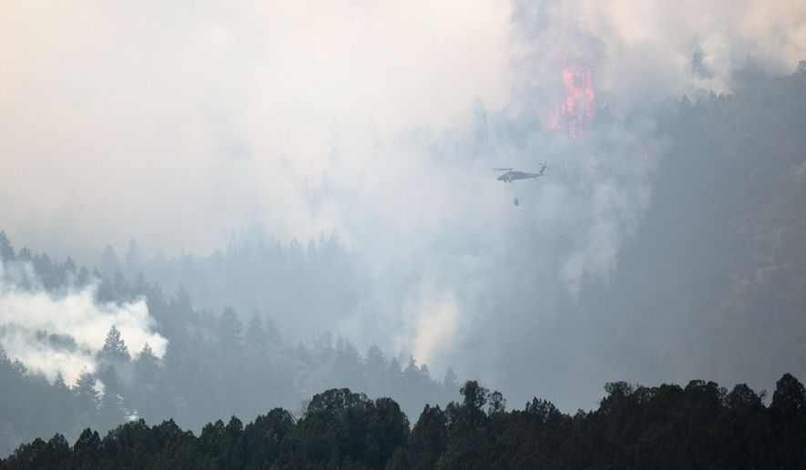 This photo taken Aug. 6, 2018, shows a helicopter heads out to dump water on the Coal Hollow Fire near U.S. Highway 6. An Idaho prisoner sent to help fight a wildfire in Utah raped a woman who also was working to support firefighters, prosecutors said Tuesday, Sept. 4, 2018. The woman had rejected several advances from Ruben Hernandez, 27, in the days before the Aug. 29 assault at the base camp, Sanpete County attorney Kevin Daniels said. Hernandez has been charged with felony rape. (Evan Cobb/The Daily Herald via AP)