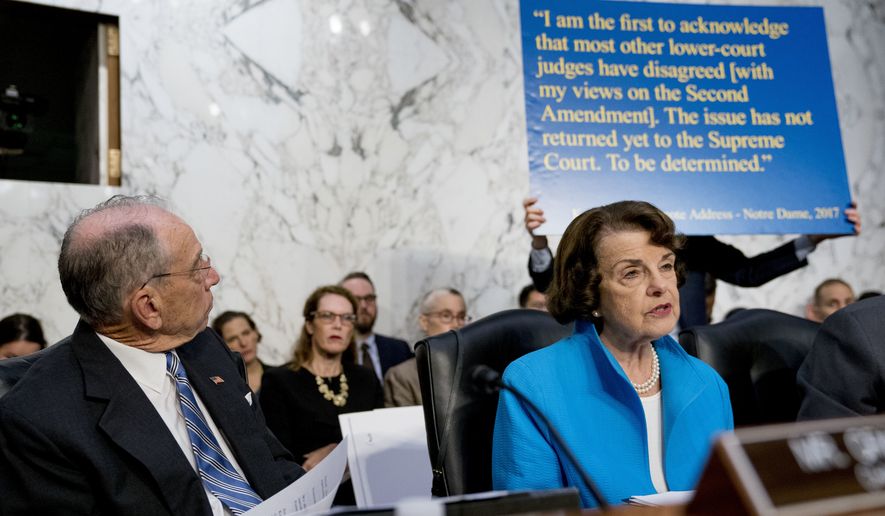 A poster depicting a 2017 quote on the Second Amendment by President Donald Trump&#39;s Supreme Court nominee, Brett Kavanaugh, a federal appeals court judge, is held up behind Sen. Dianne Feinstein, D-Calif., the ranking member on the Senate Judiciary Committee, right, as she questions Kavanaugh as he testifies before the Senate Judiciary Committee on Capitol Hill in Washington, Wednesday, Sept. 5, 2018, for the second day of his confirmation to replace retired Justice Anthony Kennedy. Also pictured is Senate Judiciary Committee Chairman Chuck Grassley, R-Iowa, left. (AP Photo/Andrew Harnik)