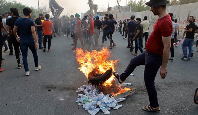 Protesters set a tire on fire in front of the provincial council building during protests demanding better public services and jobs, Tuesday, Sept. 4, 2018, in Basra, 340 miles (550 kilometers) southeast of Baghdad, Iraq. Iraqi security forces fired tear gas and live ammunition on hundreds of protesters. (AP Photo/Nabil al-Jurani)