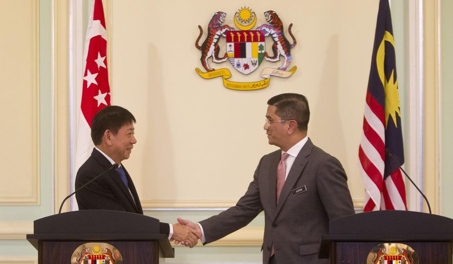 Malaysia&#39;s Minister of Economic Affair Mohamed Azmin Ali, right, and Minister for Infrastructure and Minister for Transport of Singapore Khaw Boon Wan shake hands during a press conference at Prime Minister Office in Putrajaya, Malaysia, Wednesday, Sept. 5, 2018. A planned high-speed railway that would cut travel time between Kuala Lumpur and Singapore to just 90 minutes will now be deferred for two years, instead of being axed, the two governments said. (AP Photo/Yam G-Jun)