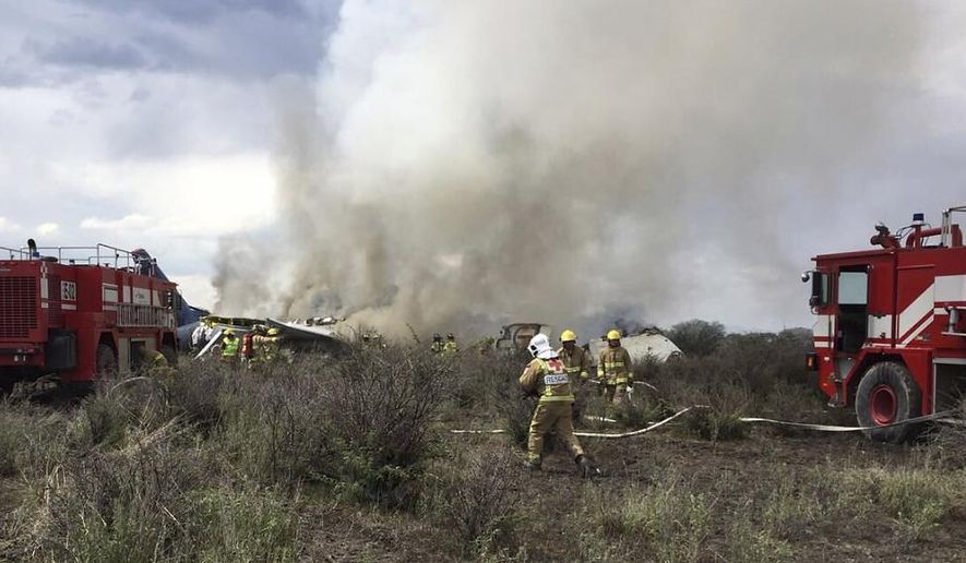 FILE- In this July 31, 2018 file photo, rescue workers and firefighters are seen at the site where an Aeromexico airliner has suffered an "accident" in a field near the airport of Durango, Mexico. The Transportation department said, Wednesday, Sept. 5, that there was no evidence of pilot error, but acknowledged a trainee was improperly seated in the co-pilot’s seat when the plane took off. It said the plane’s commanding officer took over controls from the trainee just before the crash. (Civil Defense Office of Durango Photo via AP, File)