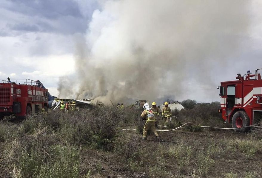 FILE- In this July 31, 2018 file photo, rescue workers and firefighters are seen at the site where an Aeromexico airliner has suffered an "accident" in a field near the airport of Durango, Mexico. The Transportation department said, Wednesday, Sept. 5, that there was no evidence of pilot error, but acknowledged a trainee was improperly seated in the co-pilot’s seat when the plane took off. It said the plane’s commanding officer took over controls from the trainee just before the crash. (Civil Defense Office of Durango Photo via AP, File)