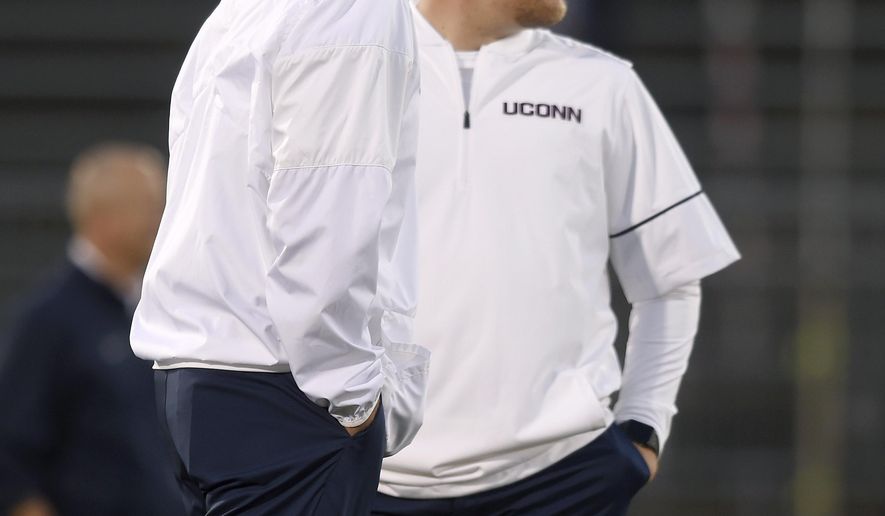 In this Oct. 6, 2017, photo, Connecticut football head coach Randy Edsall, left, talks with his son Corey, the tight ends coach, before an NCAA football game against Memphis in East Hartford. Conn. A New Britain Superior Court judge is set to hear arguments Wednesday, Sept. 5, 2018, whether Randy Edsall should be allowed to retain his son as an assistant coach on the team. Edsall is appealing a ruling by the state&#39;s ethics office that the school violated Connecticut&#39;s ban on nepotism by hiring his son in 2017 as an assistant coach. (John Woike/Hartford Courant via AP)