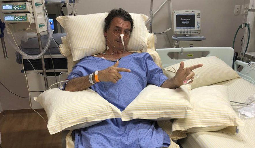 In this handout photo provided by the National Social Liberal Party press office, presidential candidate Jair Bolsonaro poses for a photo while sitting in his hospital room at the Albert Einstein Hospital, in Sao Paulo, Brazil, Saturday, Aug. 8, 2018. The far-right congressman was stabbed on Thursday during a campaign rally. Bolsonaro, 63, suffered intestinal damage and serious internal bleeding, according to Dr. Luiz Henrique Borsato, one of the surgeons who operated on the candidate. (Flavio Bolsonaro/National Social Liberal Party via AP)
