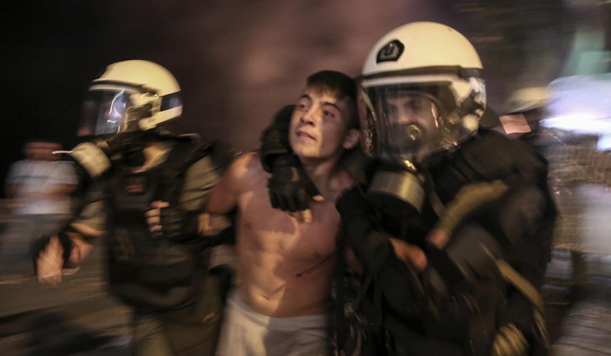 A protester is detained by riot policemen during clashes at the northern Greek city of Thessaloniki, Saturday, Sept. 8, 2018. Police in northern Greece have clashed with protesters outside an international trade fair where prime minister Tsipras made a keynote speech. (AP Photo/Dimitris Tosidis)
