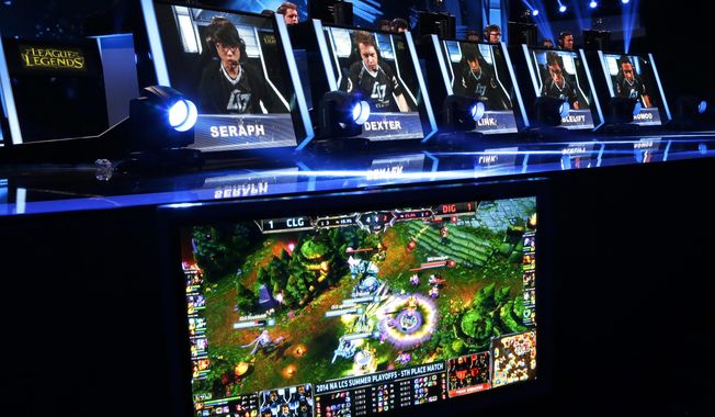 FILE - In this Aug. 29, 2014, file photo, names and faces of gamers are shown as they compete in a round of the League of Legends championship series video game competition at the Penny Arcade Expo, a fan-centric celebration of gaming in Seattle. The head of North American esports operations for Riot Games has a message for concerned League of Legends fans: “We’re not cutting budget.”   (AP Photo/Ted S. Warren, File)