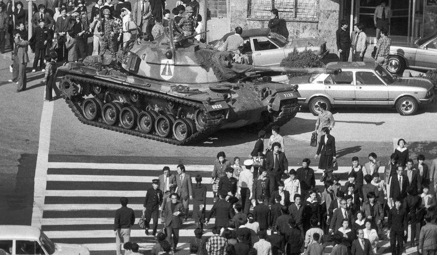 FILE - In this Oct. 27, 1979, file photo, people walk beside a South Korean army tank after martial law was declared following the death of South Korean President Park Chung-hee in Seoul, South Korea. Former Associated Press photojournalist Kim Chonkil, whose images captured South Korea&#39;s turbulent transition from dictatorship to democracy, has died. He was 89. Kim&#39;s son, Kim Kuchul, confirmed he died in New York on Thursday, Sept. 6, 2018. (AP Photo/Kim Chonkil, File)