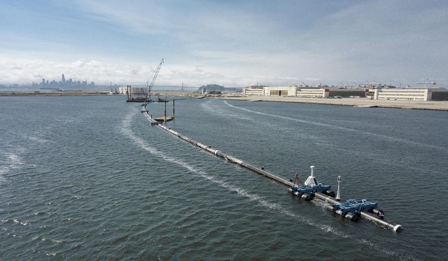 In this Monday, Aug. 27, 2018 photo provided by The Ocean Cleanup, a long floating boom that will be used to corral plastic litter in the Pacific Ocean is assembled in Alameda, Calif. Engineers will deploy a trash collection device to corral plastic litter floating between California and Hawaii in an attempt to clean up the world's largest garbage patch. The 2,000-foot (600-meter) long floating boom will be towed Saturday, Sept. 8, 2018, from San Francisco to the Great Pacific Garbage Patch, an island of trash twice the size of Texas. (The Ocean Cleanup via AP)