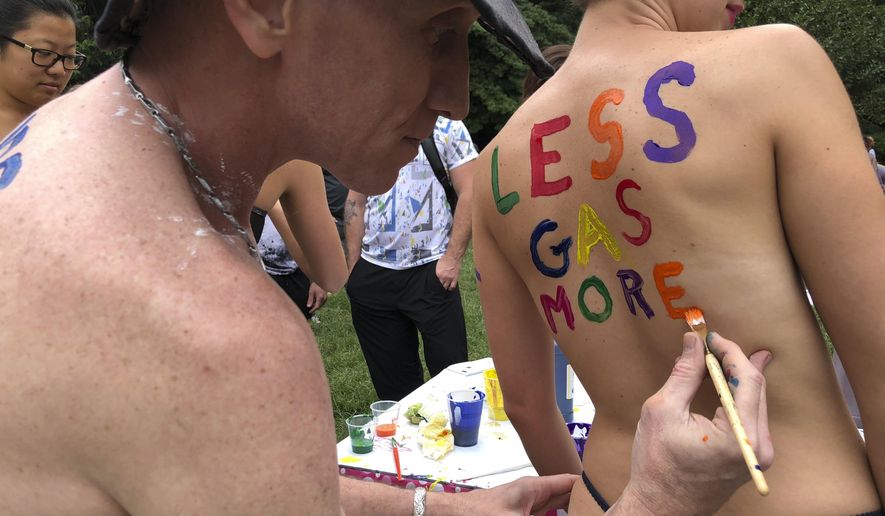 Bicyclist Olivia Neely gets a message advocating for less consumption of fossil fuels painted on her back at the Philly Naked Bike Ride in Philadelphia, Saturday, Sept. 8, 2018. (AP Photo/Dino Hazell)