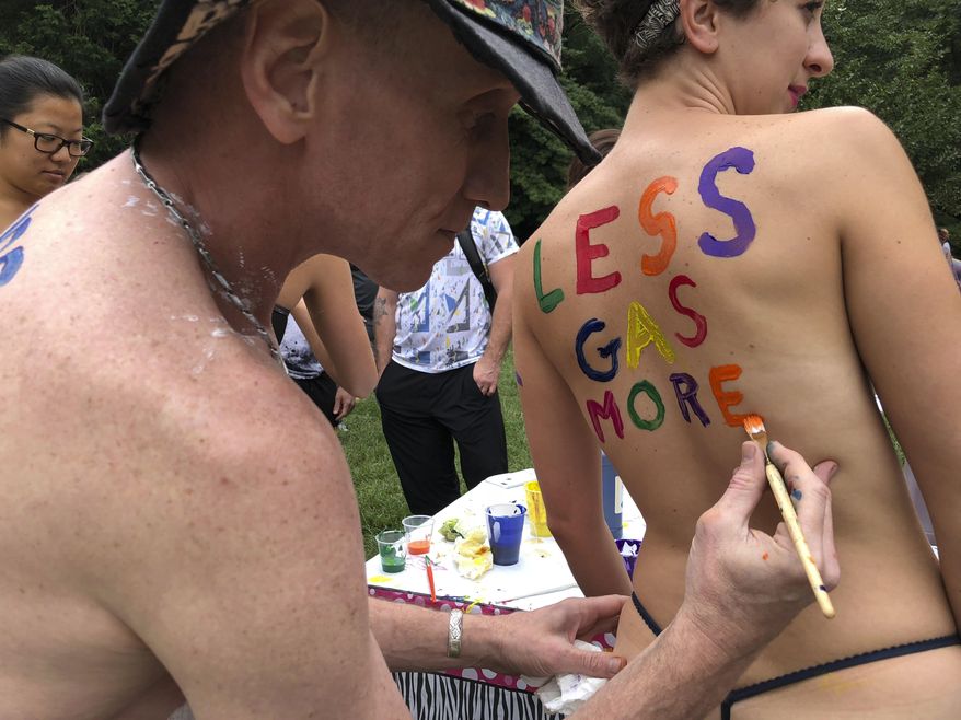 Bicyclist Olivia Neely gets a message advocating for less consumption of fossil fuels painted on her back at the Philly Naked Bike Ride in Philadelphia, Saturday, Sept. 8, 2018. (AP Photo/Dino Hazell)