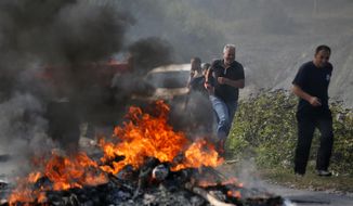 Kosovo Albanians run past a fire burning at a roadblock in Vojtesh, Kosovo, Sunday, Sept. 9, 2018. Kosovo Albanians burned tires and blocked roads with wooden logs, trucks and heavy machinery on a planned route by Serbia&#39;s President Aleksandar Vucic who was trying to reach the village of Banje while visiting Serbs in the former Serbian province. (AP Photo/Visar Kryeziu)