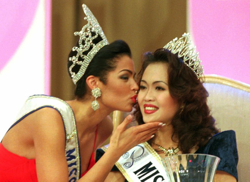 FILE- In this Jan. 19, 1996, file photo, reigning Miss Universe 1995 Chelsi Smith, left, gives a congratulatory kiss to Adeline Ong Siew Fong, 23, after being crowned as Miss Malaysia/Universe in Kuala Lumpur. Local media cites a statement by the family of Smith that says the pageant winner died Saturday at 45-years-old following a long-term illness. (AP Photo/C.F. Tham, File)