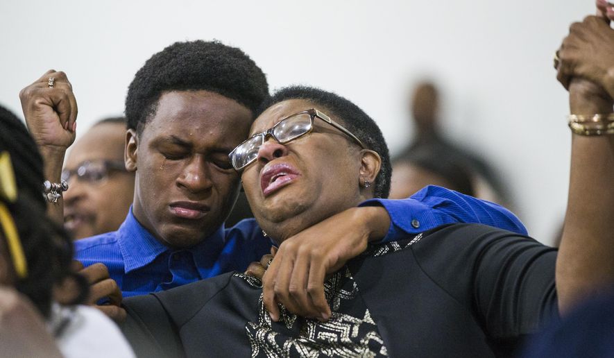 Allison Jean raises her hands in the air as she leans on her son, Grant, 15, during a prayer service for her son and Grant's brother Botham Jean at the Dallas West Church of Christ on Sunday, Sept. 9, 2018 in Dallas. Botham Jean was shot and killed by Dallas police officer Amber Guyger in his apartment on Thursday night. (Shaban Athuman/The Dallas Morning News via AP)