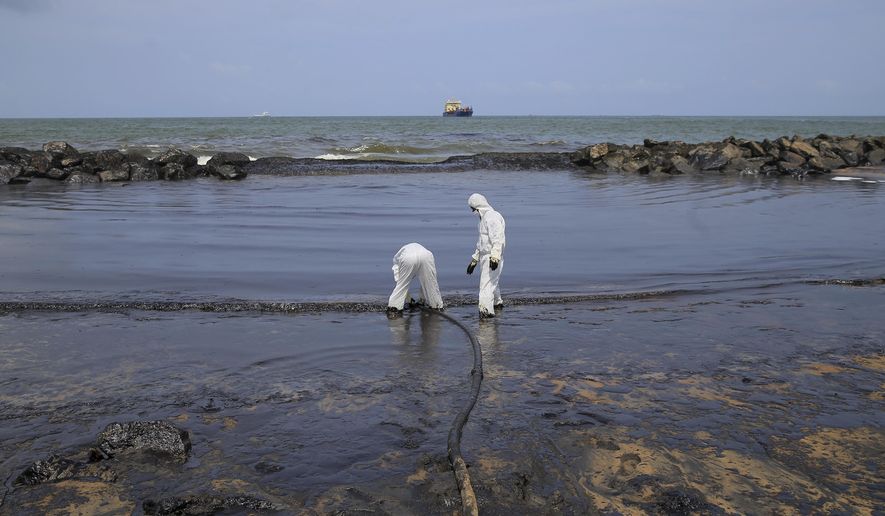 Sri Lankan coast guard personnel in protective clothes work to remove oil from a beach following an oil spill in Uswetakeiyawa, a coastal town north of Colombo, Sri Lanka, Monday, Sept. 10, 2019.Sri Lanka deployed hundreds of coast guard and navy personnel on Monday to clean oil slicks on a coastal stretch near the capital following a spill caused by a pipeline leak. (AP Photo/Eranga Jayawardena)