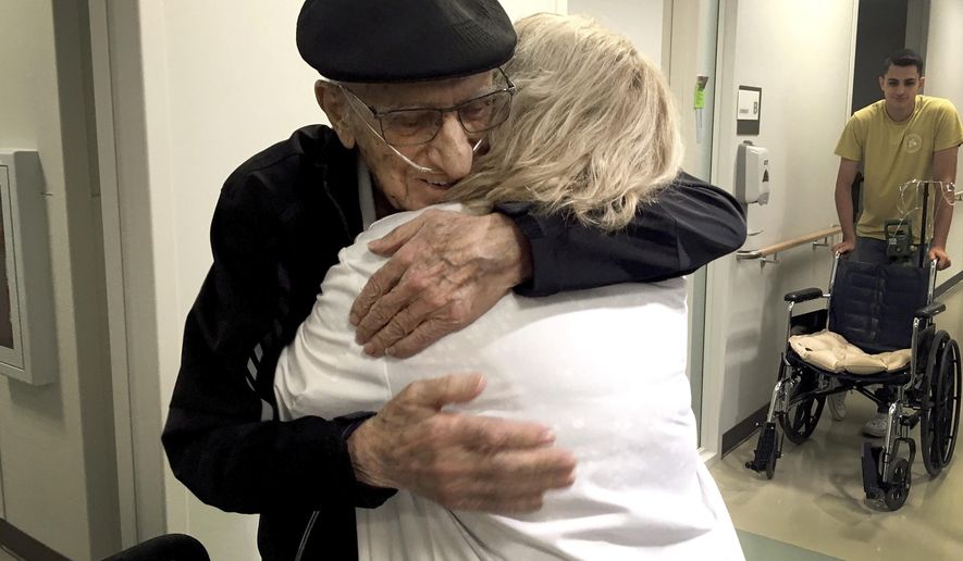 The Rev. John Sabbagh, left, and his son Ebby Sabbagh hugs nurse practitioner Kim O&#39;Riley, Friday, Sept. 7, 2018 in Gilbert, Ariz. Thirty-five years after a Mesa man cared for his son when he was shot in their native Lebanon, the son is returning that devotion. Both the Rev. John Ibraham Sabbagh and his 54-year-old son, Ebby Sabbagh, are celebrating one year of going strong since the elder Sabbagh received a crucial stem-cell transplant. (AP Photo/Terry Tang)