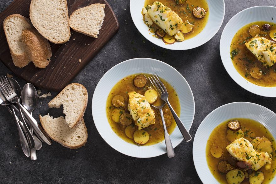 This undated photo provided by America's Test Kitchen in August 2018 shows cod in saffron broth with chorizo and potatoes in Brookline, Mass. This recipe appears in the cookbook “Dinner Illustrated.” (Steve Klise/America's Test Kitchen via AP)