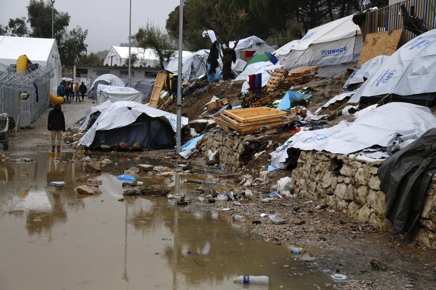 FILE - In this Tuesday, Jan. 10, 2017 file photo, a refugee stands next to a pool of mud at Moria refugee camp on the eastern Greek island of Lesbos. Greek regional authorities are threatening to shut an infamous migrant camp on the Aegean Sea island of Lesbos unless the government takes quick action to improve conditions there. The northern Aegean regional authority says the Moria camp is “unsuitable and a threat to public health and the environment.” (Petros Tsakmakis/InTime News via AP, file)